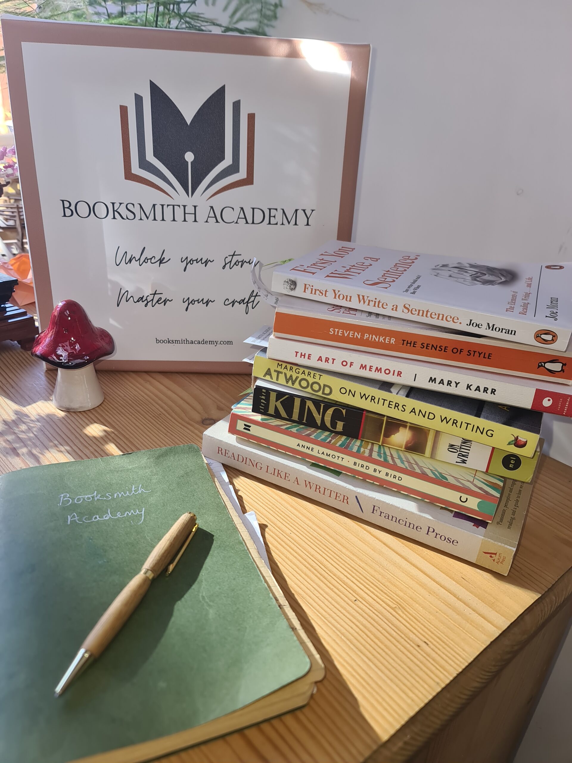 A little stack of the writing books we are discussing, and a green notebook with a gold pen laid on top
